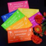 A bunch of different colored chocolate bars next to some flowers