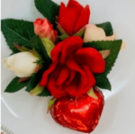 A red heart and some white roses on a plate.