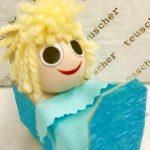 A doll with blonde hair sitting in a box.