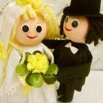 A bride and groom doll are holding flowers.