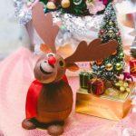 A reindeer figurine sitting next to a christmas tree.