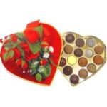 A heart shaped box of chocolates and roses.