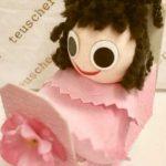 A doll in a box with pink flowers