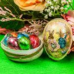 A bowl of chocolate eggs and a basket with easter bunnies.