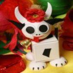 A white figurine with horns and a red flower on it.