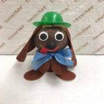 A brown dog with a green hat and blue bow.