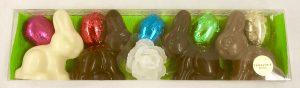 A close up of three chocolate bunnies with a white rose
