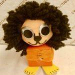A paper mache lion with long hair and orange eyes.