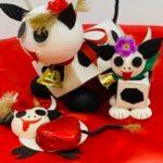 A group of cow figurines sitting on top of a red blanket.