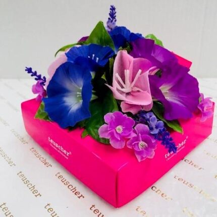 A pink box with purple and blue flowers on top of it.