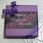 A box of truffles with purple ribbon around it.