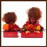 Two boxes with flowers and feathers on top of them.