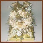 A gold box with flowers and ribbons on top.