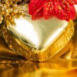 A heart shaped box with a red bow on top of it.