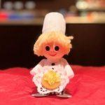 A pastry chef doll sitting on top of a table.