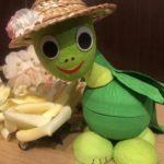 A stuffed turtle wearing a straw hat next to bananas.