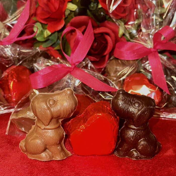 Three bags of chocolate hearts are on a table.