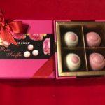 A box of four chocolates in pink and white.