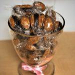 A glass of chocolate covered nuts in a pink bow.