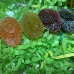 A group of different colored candies sitting on top of green shredded paper.