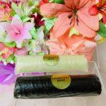 A roll of cake and a roll of pastry in front of some flowers.