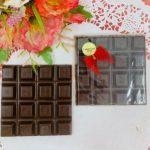 Two square chocolate bars sitting next to each other.