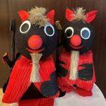 Two black and red stuffed animals sitting on top of a table.