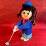 A wooden doll with a blue outfit and a hat.