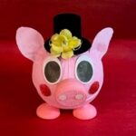 A pink piggy bank with a black top hat on it's head.